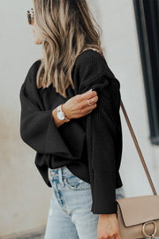 Black textured knit sweater with slit sleeves and a relaxed fit.