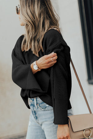 Black textured knit sweater with slit sleeves and a relaxed fit.