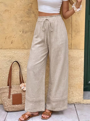 Beige maternity wide-leg trousers with drawstring and lace trim detail.