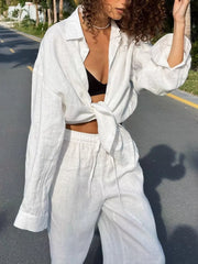 White linen relaxed fit button-up shirt tied at waist and matching drawstring pants.