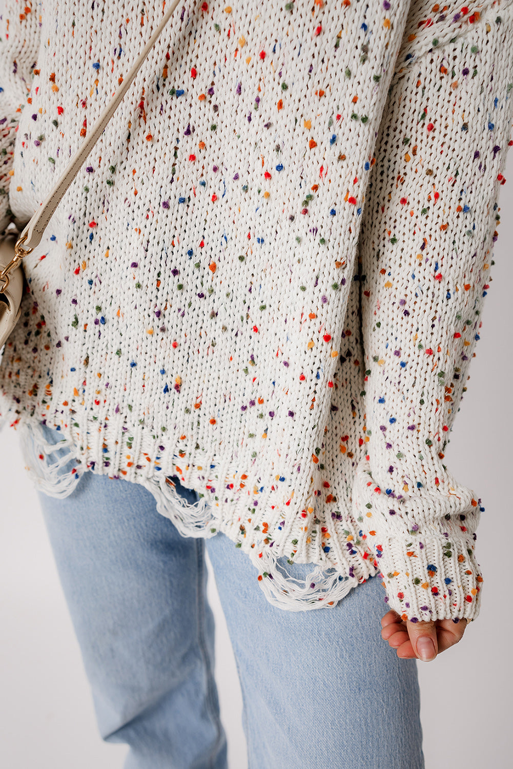 Confetti knit sweater in white with colorful flecks and distressed hem detail.