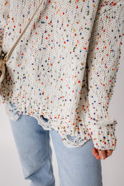 Confetti knit sweater in white with colorful flecks and distressed hem detail.