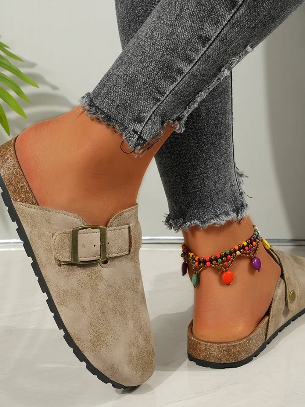 Beige suede mules with buckle detail and cork sole, styled with distressed jeans.
