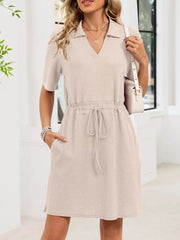 Textured polo dress in apricot with short sleeves, V-neck, adjustable drawstring waist, and pockets.