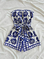 Blue floral tie-waist strapless romper with ruffled hem and tie detail.