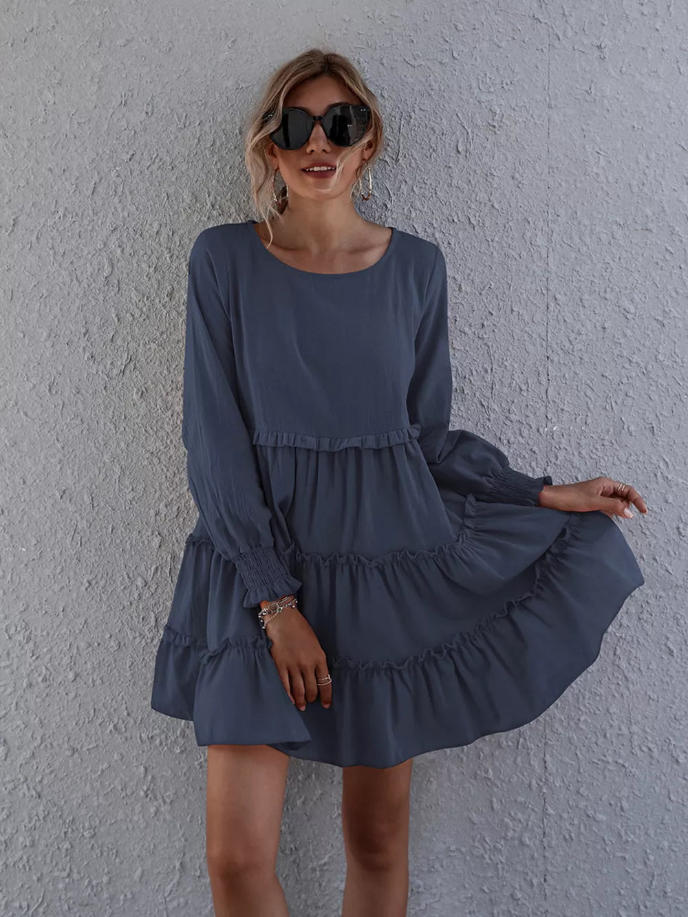 Navy blue ruffled mini dress with long sleeves and tiered skirt.
