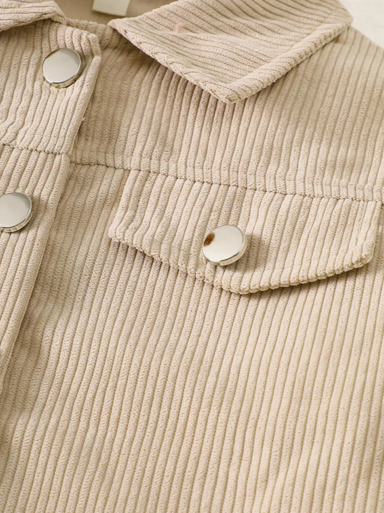 Tan corduroy button-up jacket with silver buttons and chest pockets.