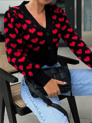 Black knit cardigan with red hearts, puff sleeves, and V-neck.