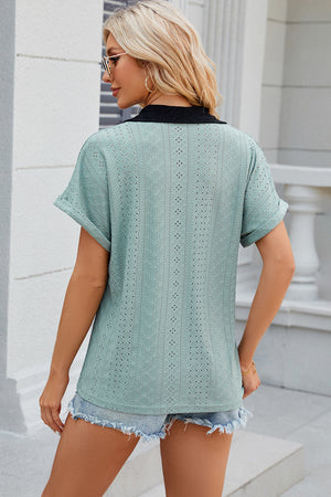 Light green perforated panel polo top with black collar and cuffed short sleeves.