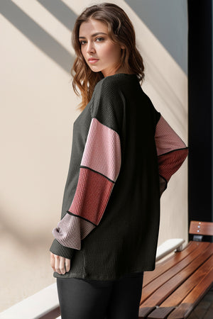 Waffle knit henley shirt in black with colorblock sleeves in pink and red tones.