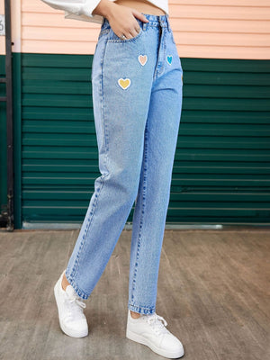 Light wash denim jeans with colorful heart patches and a straight leg cut.