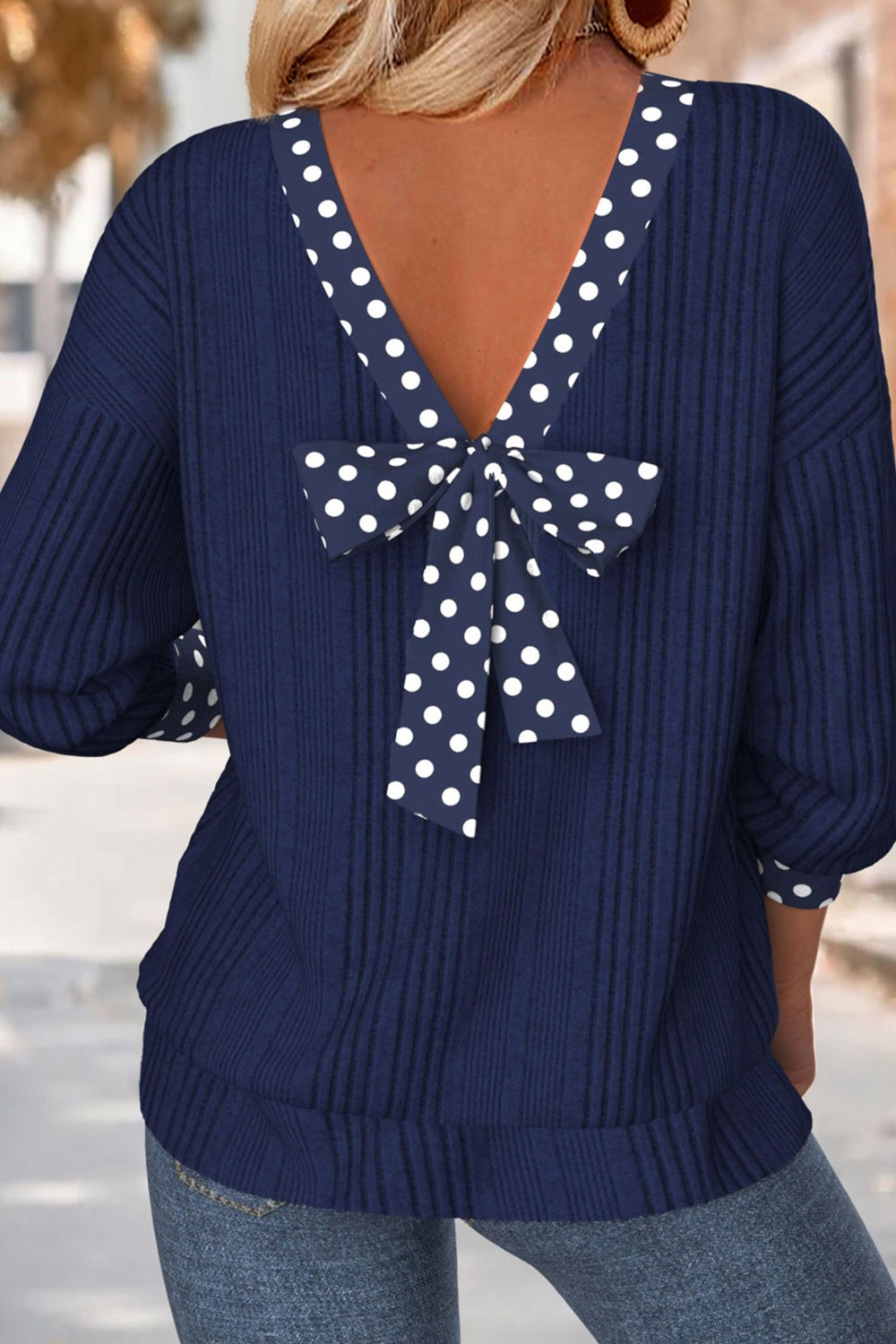 Navy polka dot bowknot backless blouse with ribbed texture and long sleeves.