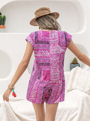 Bohemian print playsuit in red-violet with cap sleeves and a buttoned front, styled casually.