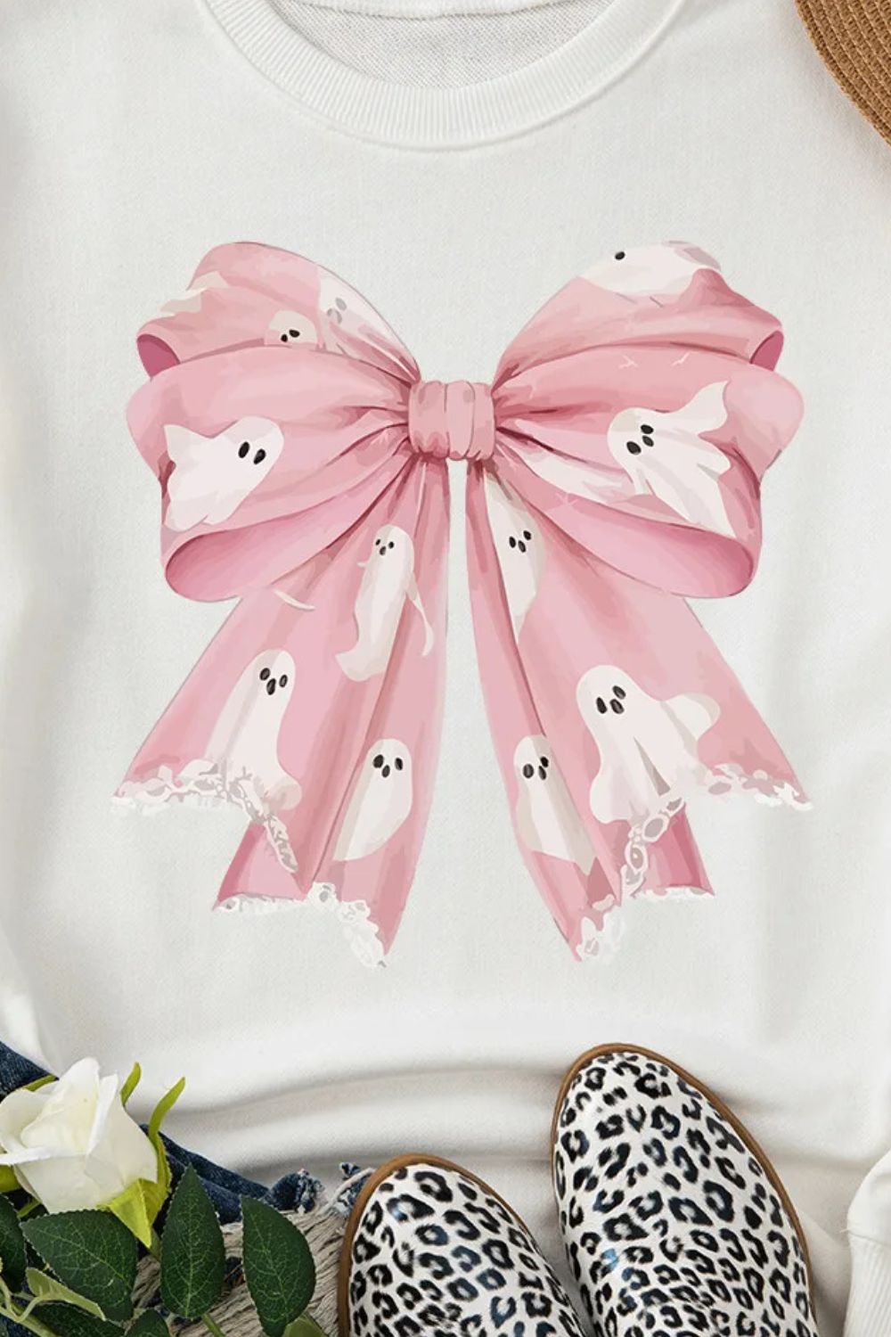 White crewneck sweatshirt with a pink bow graphic featuring ghost designs and lace trim.