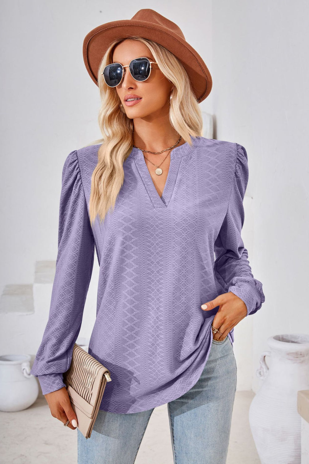 Textured lilac blouse with bishop sleeves and V-neck, styled with jeans and a clutch.