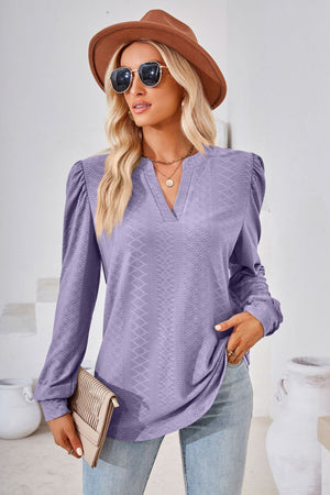 Textured lilac blouse with bishop sleeves and V-neck, styled with jeans and a clutch.