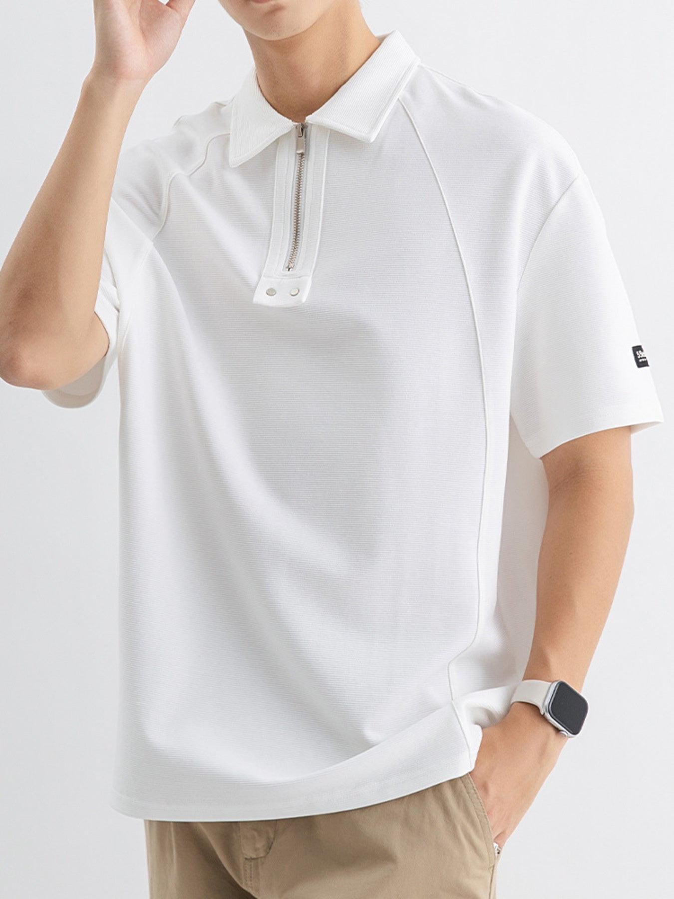 White cotton polo with half-zip metallic accent and subtle texture.