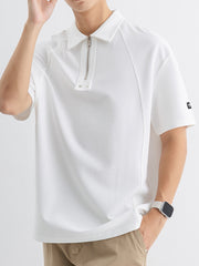 White cotton polo with half-zip metallic accent and subtle texture.