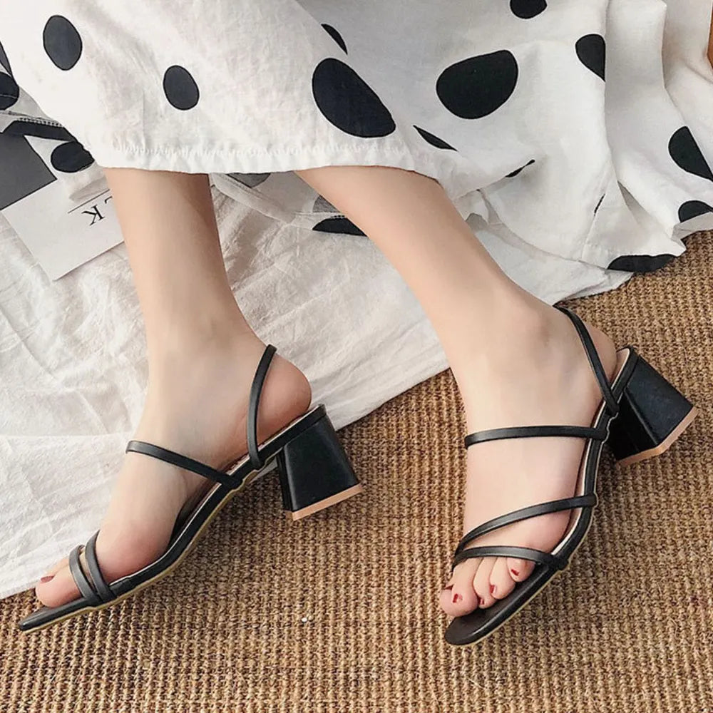 Black minimalist block heel mules with thin strappy details.
