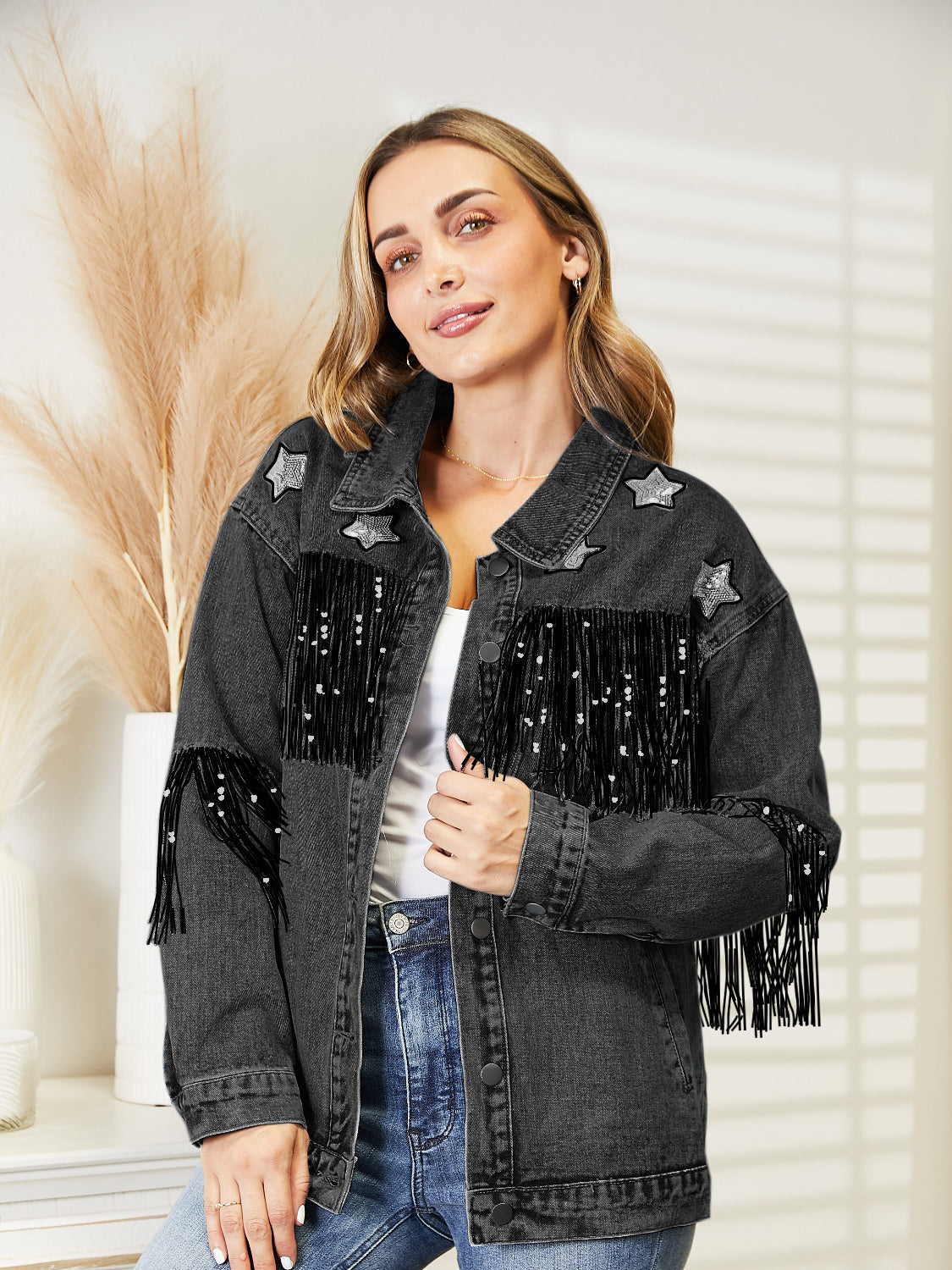 Black denim trucker jacket with star patches and sequin fringe detail.