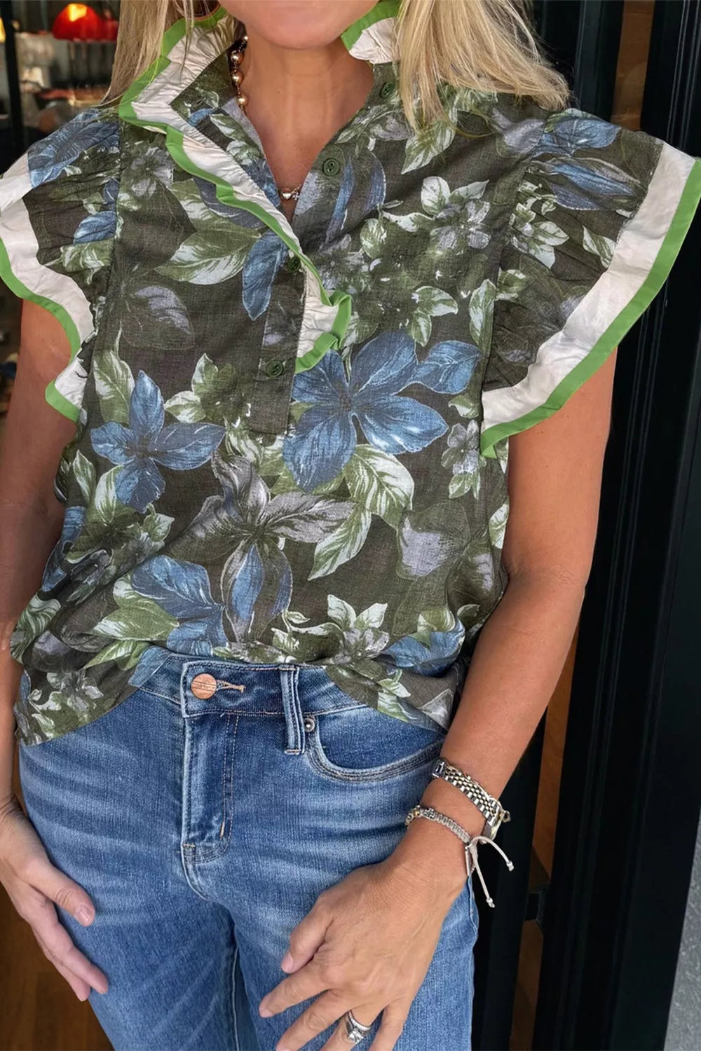 Botanical ruffle sleeve shirt in green with blue flowers, white and green trim.