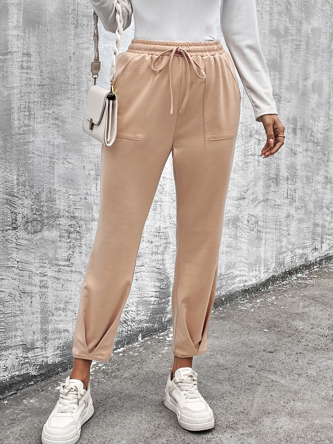 Beige utility joggers with tapered hemline, drawstring waist, and side pockets.