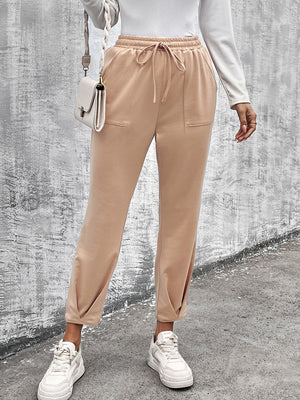 Beige utility joggers with tapered hemline, drawstring waist, and side pockets.