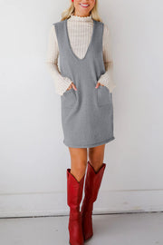 Sleeveless gray knit dress with V-neck and patch pockets, styled with a cream mock neck top.