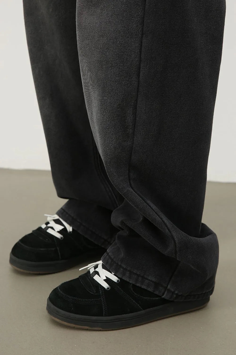 Oversized dark wash denim trousers with a relaxed fit, styled with black sneakers.