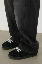 Oversized dark wash denim trousers with a relaxed fit, styled with black sneakers.