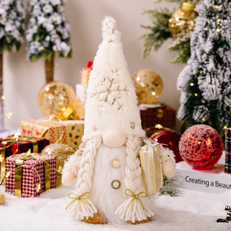 Illuminated festive gnome with white fur hat, snowflake sequins, and braided pigtails holding a gift.