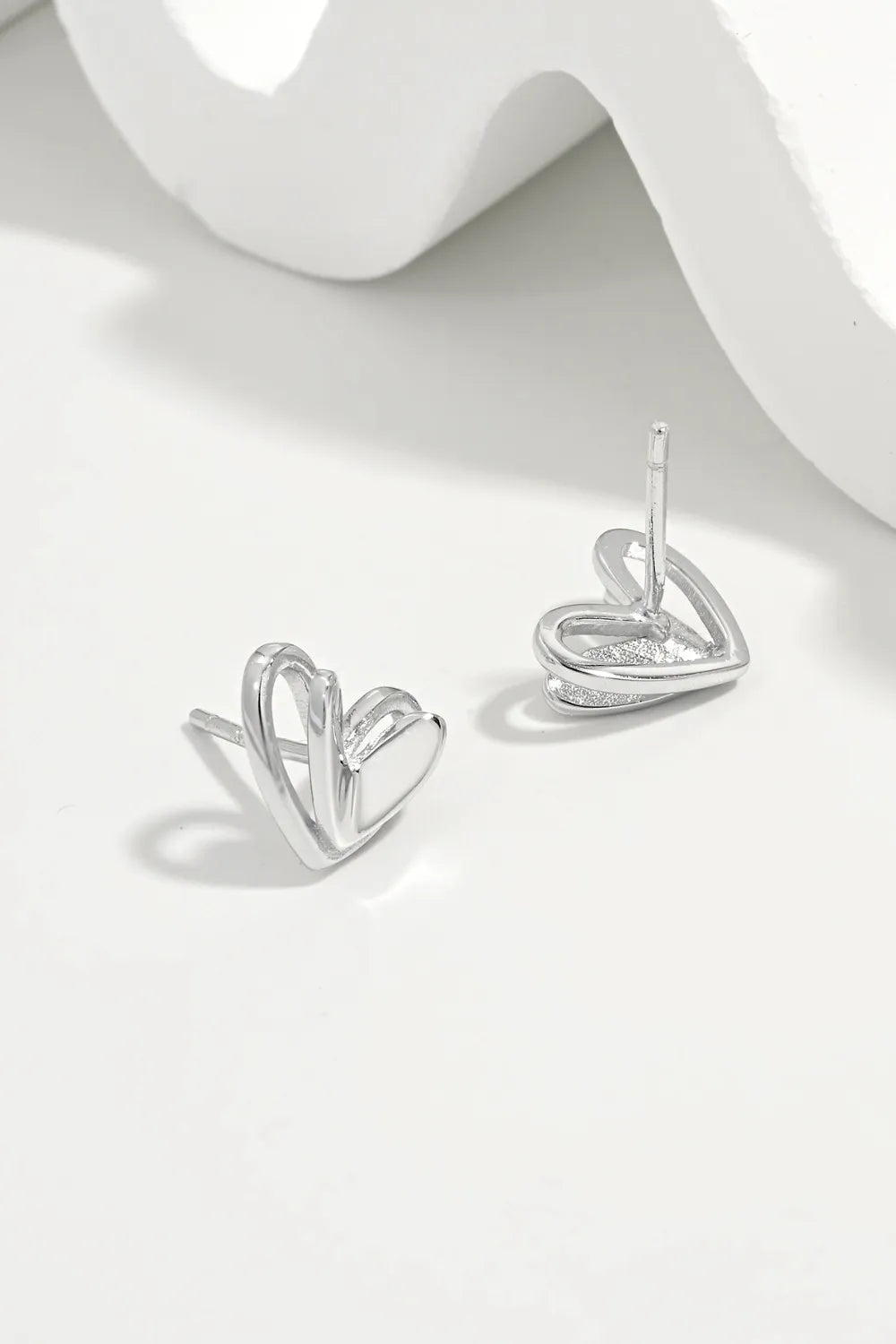 Open heart silhouette stud earrings in silver with a delicate, modern design.