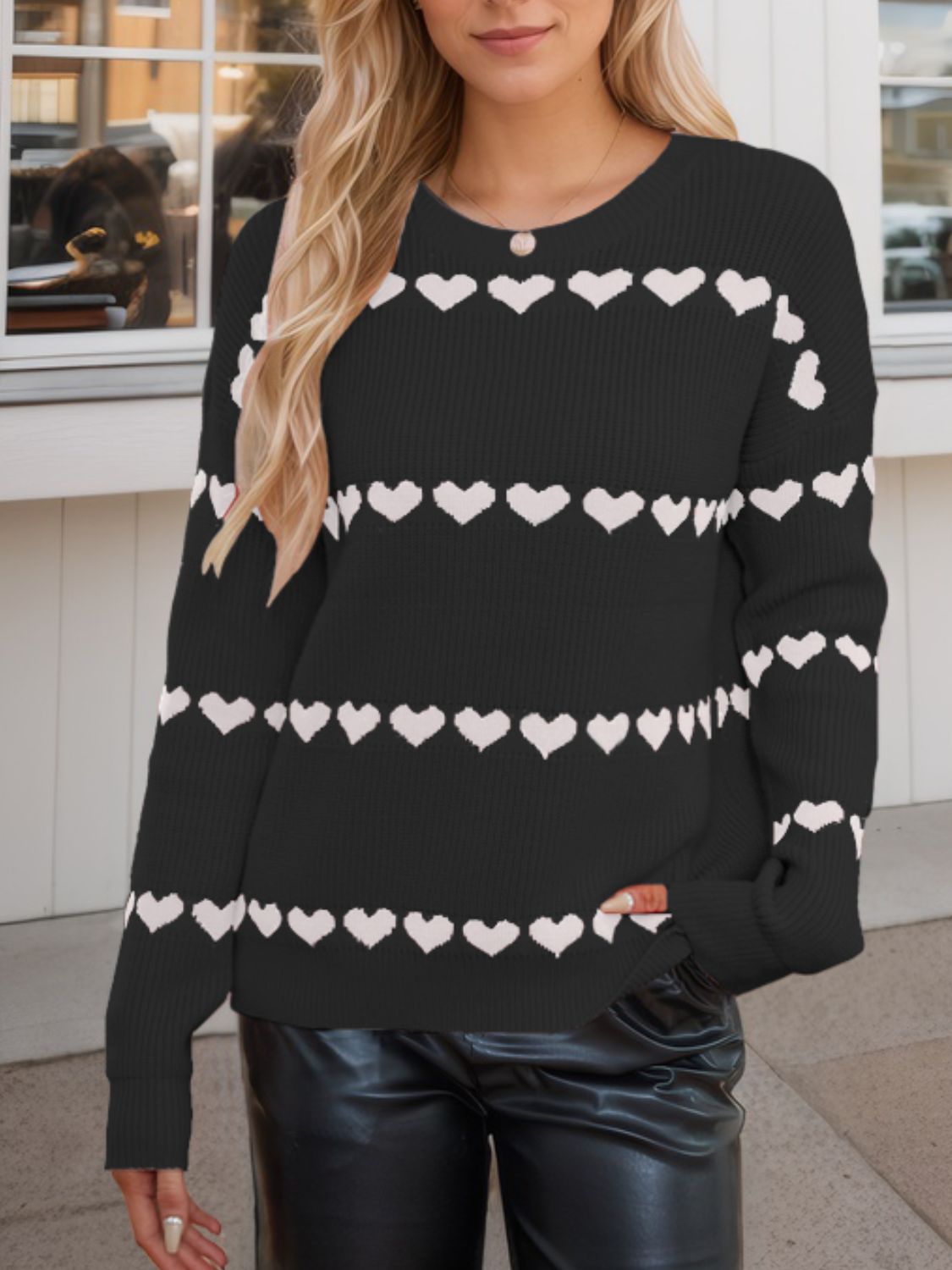 Black knit sweater with white heart stripes, crew neck, long sleeves.