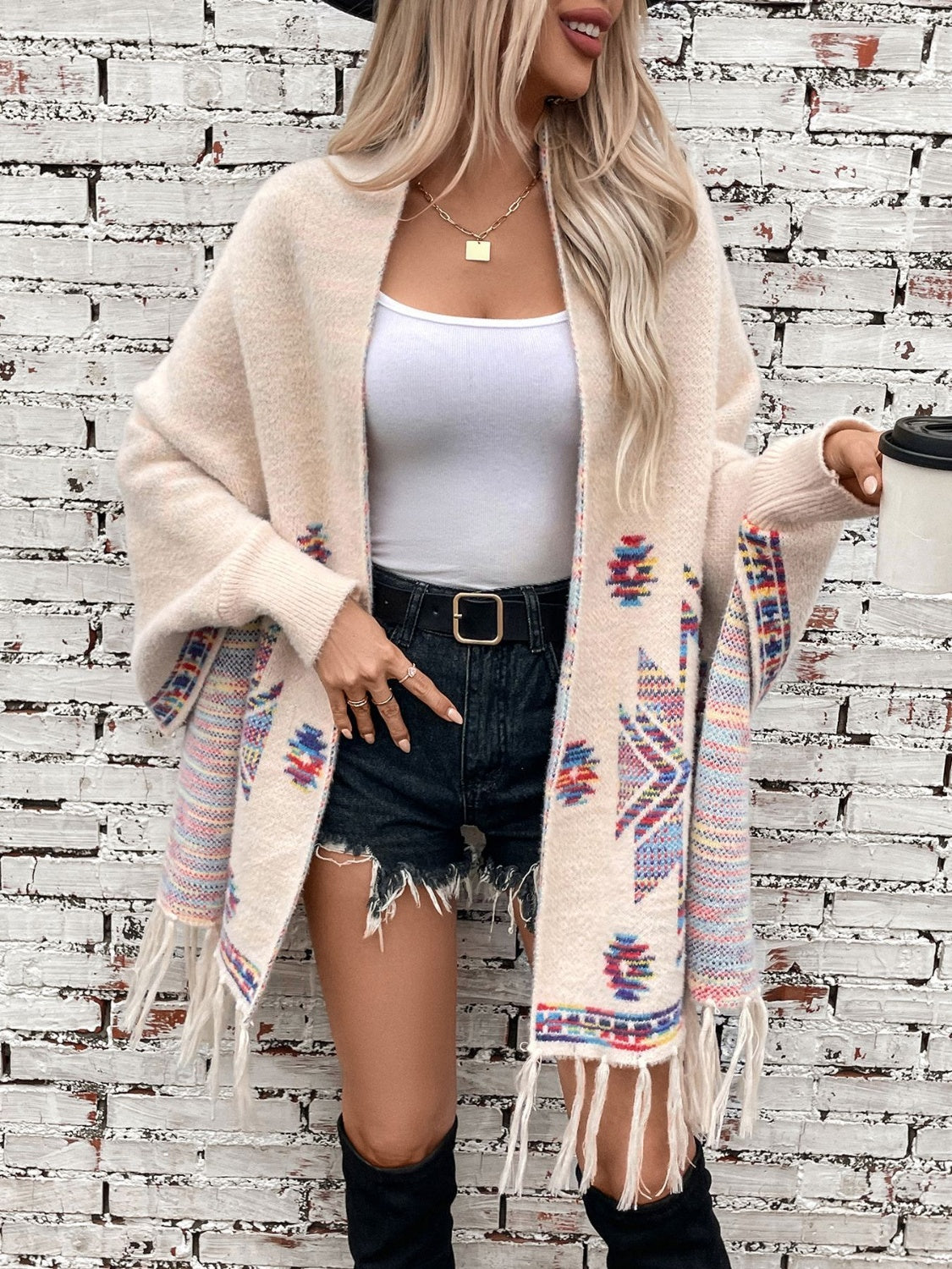Cream Aztec fringe knit cardigan with colorful geometric pattern and fringe detail.