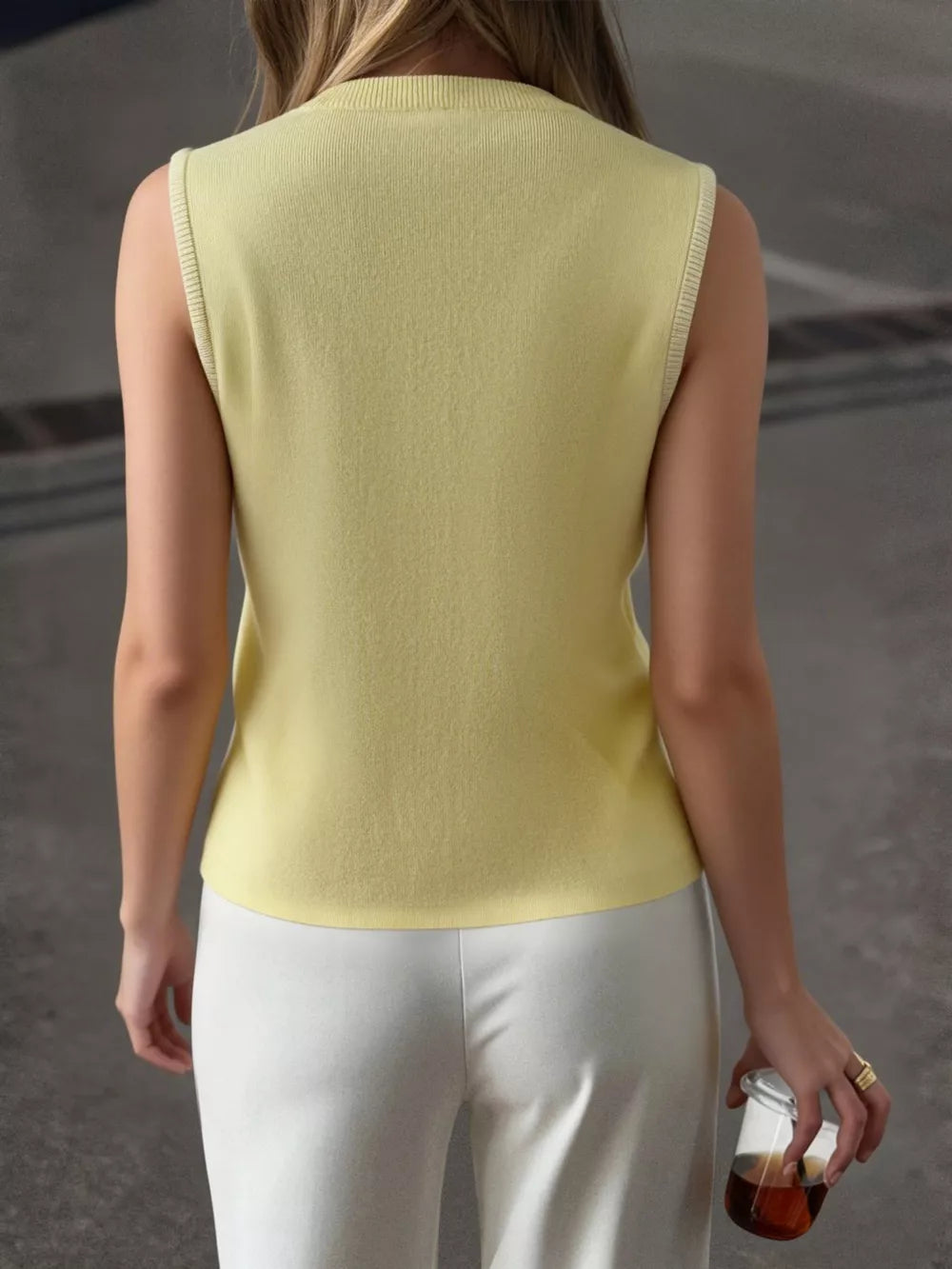 Yellow knit vest with ribbed trim, crew neck, and sleeveless design.