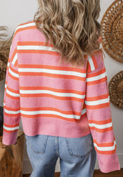 Pink and orange striped knit cardigan with white stripes, crew neck, long sleeves.