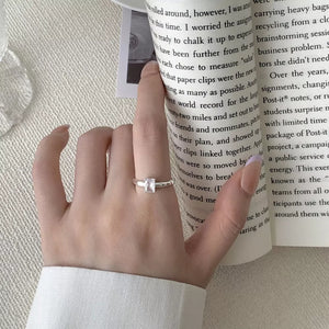 Sleek silver ring with a geometric zircon stone on a hand holding a book.