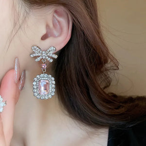 Silver bow crystal drop earrings with a pink gemstone pendant.