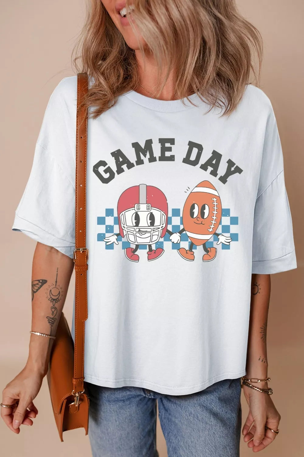 White cotton graphic t-shirt with "Game Day" text and cartoon football helmet and ball characters.
