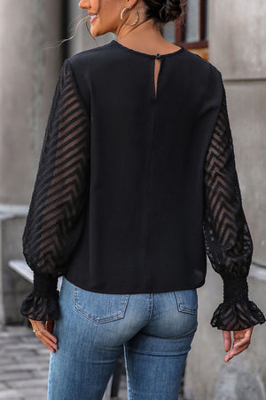 Black blouse with sheer chevron lace balloon sleeves and smocked cuffs.
