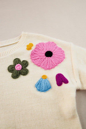 Cream knit sweater with embroidered floral appliqués in pink, green, blue, yellow, and purple.