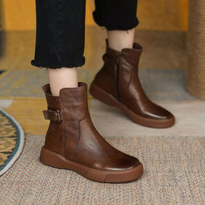 Brown leather ankle boots with round toe, decorative buckle, and side zipper.