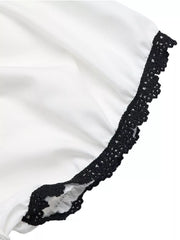White maternity blouse with black lace trim on the sleeve hem and a ruffled detail.