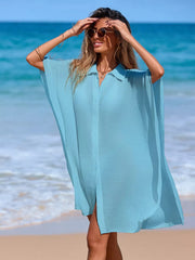 Pastel blue button-up cover-up with short sleeves and side slits, worn on the beach.