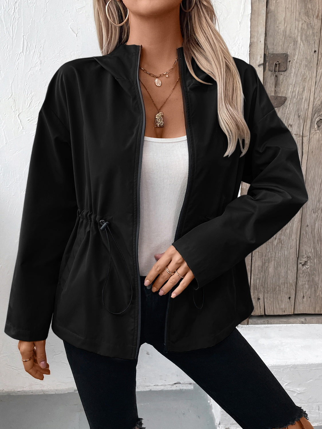 Black cinched waist utility jacket with drawstring detail and zip front, styled with a white tank top.