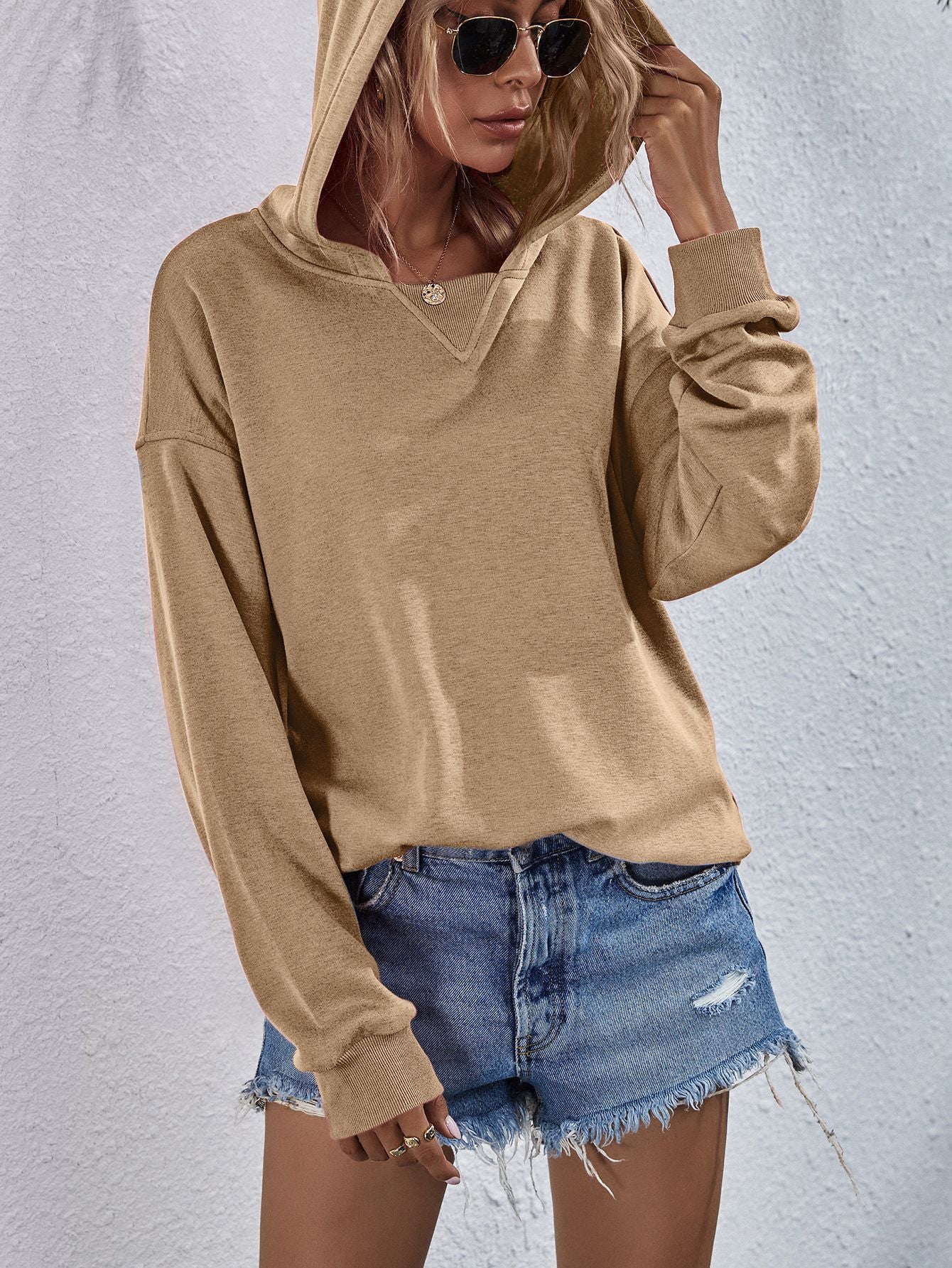 Tan boxy hooded sweatshirt with split V-neck and ribbed cuffs.
