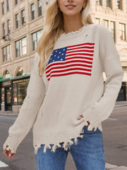 Cream knit sweater with distressed American flag graphic and frayed hem.