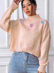 Blush pink cropped turtleneck knit sweater with embroidered flowers, ribbed cuffs and hem.