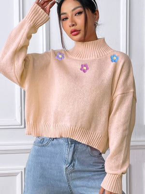 Blush pink cropped turtleneck knit sweater with embroidered flowers, ribbed cuffs and hem.
