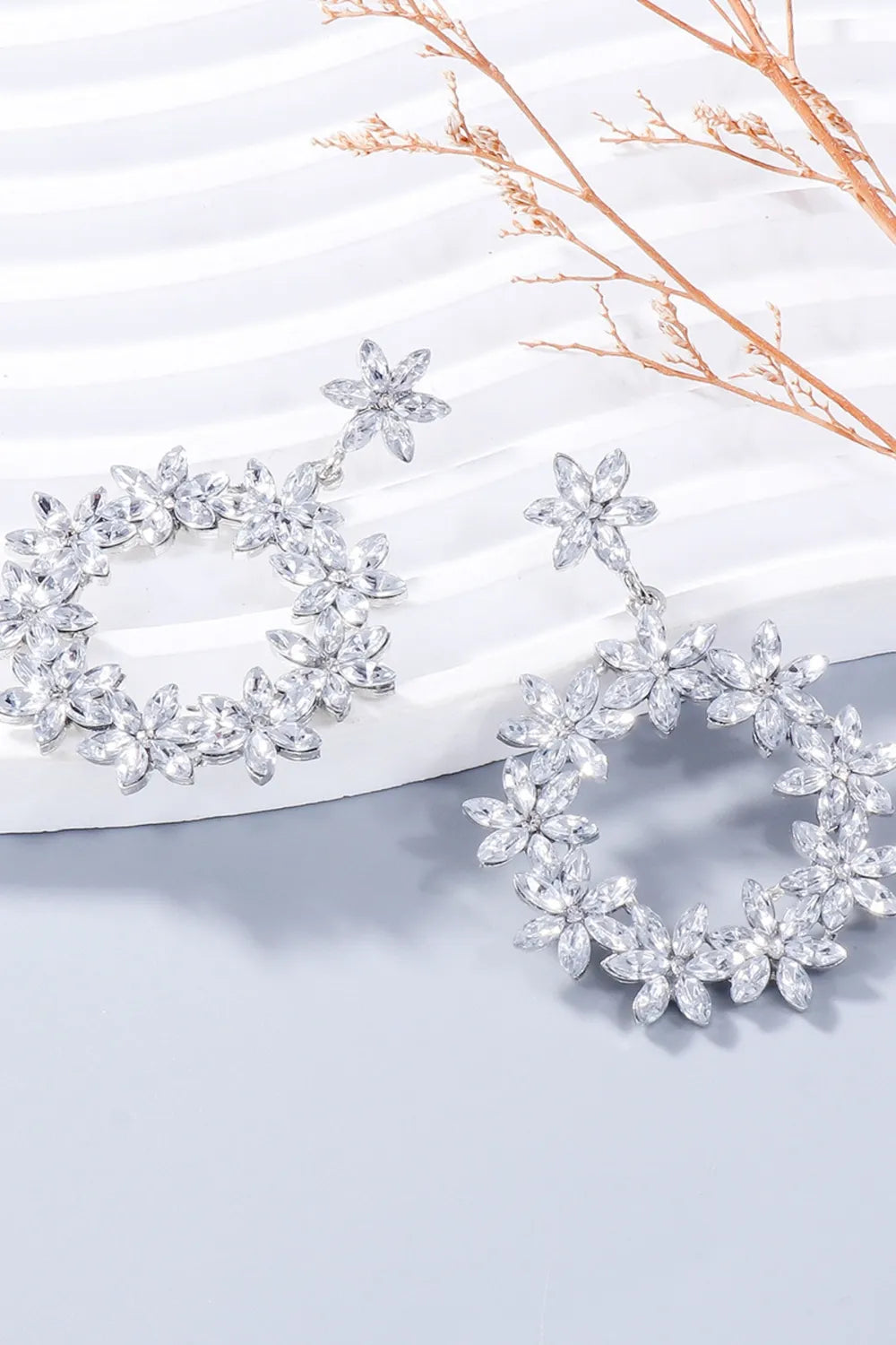 Silver floral halo drop earrings with crystal accents.